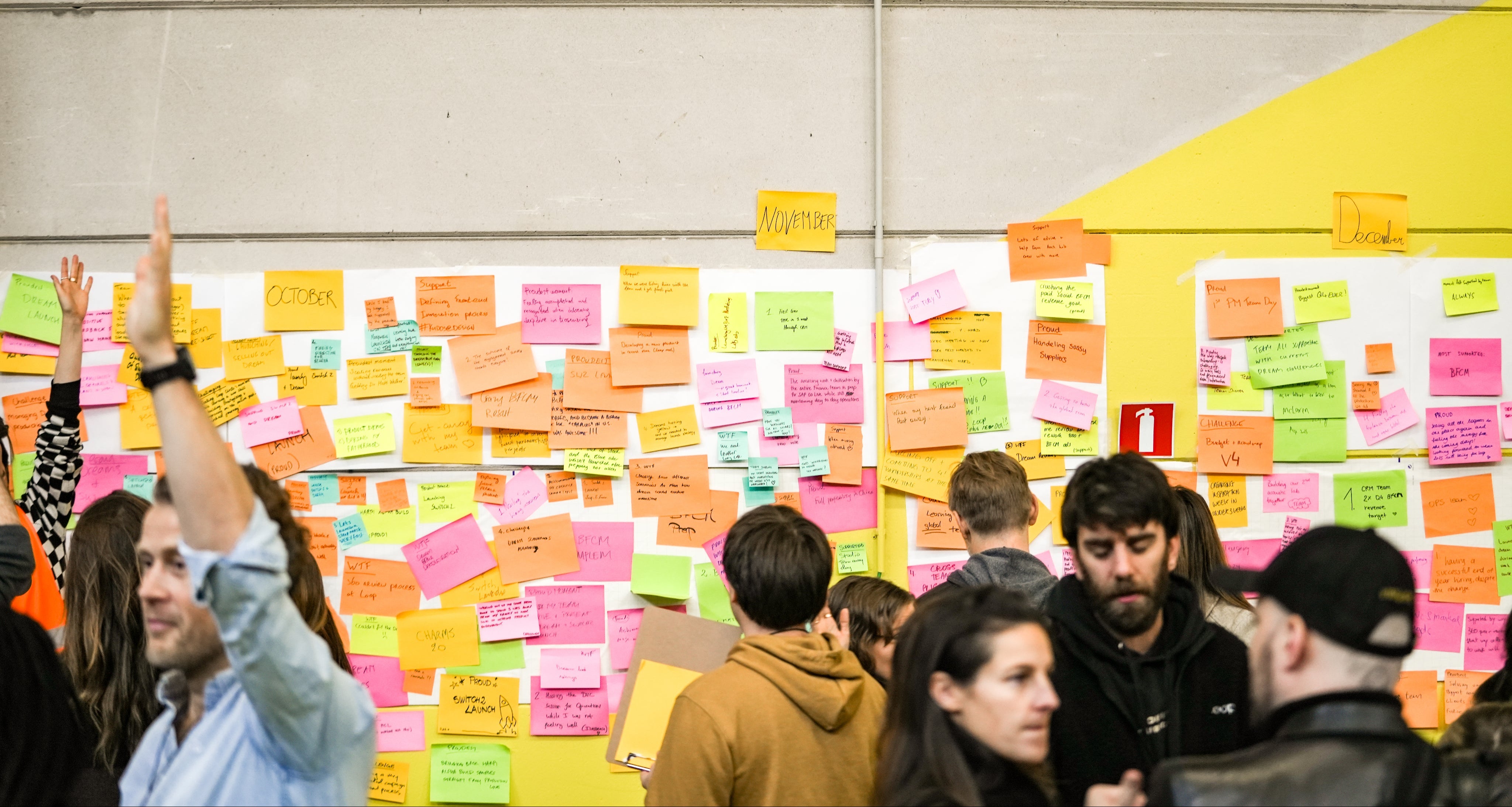 Group of people interacting with colorful sticky notes on a wall