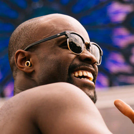 Man wearing sunglasses and Loop Experience 2 earplugs with a colorful background