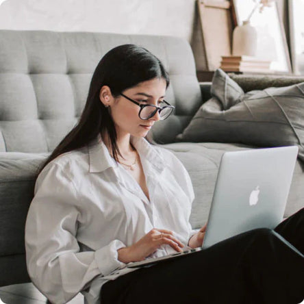 Woman using a laptop on a couch in a home setting
