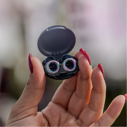 Hand holding open black case with Loop Experience 2 earplugs against a blurred background