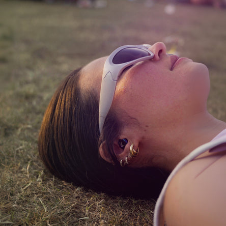Person lying on grass wearing sunglasses with a blurred background