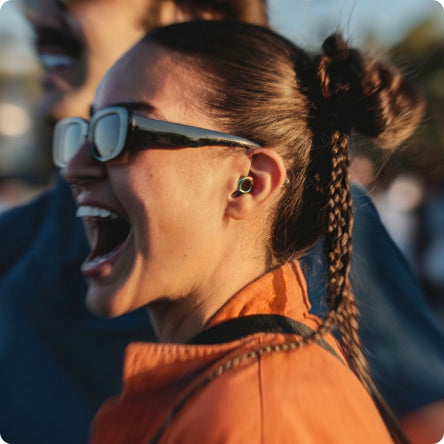 Person wearing sunglasses at a festival wearing Loop x Coachella Experience 2 earplugs