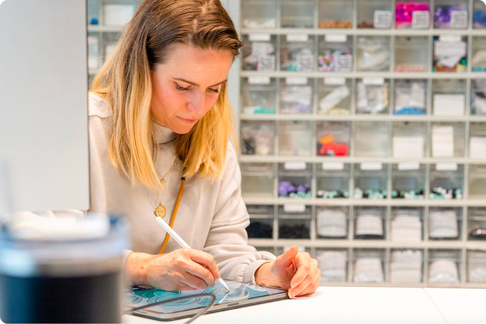 Woman working on a tablet in an office setting with shelves in the background